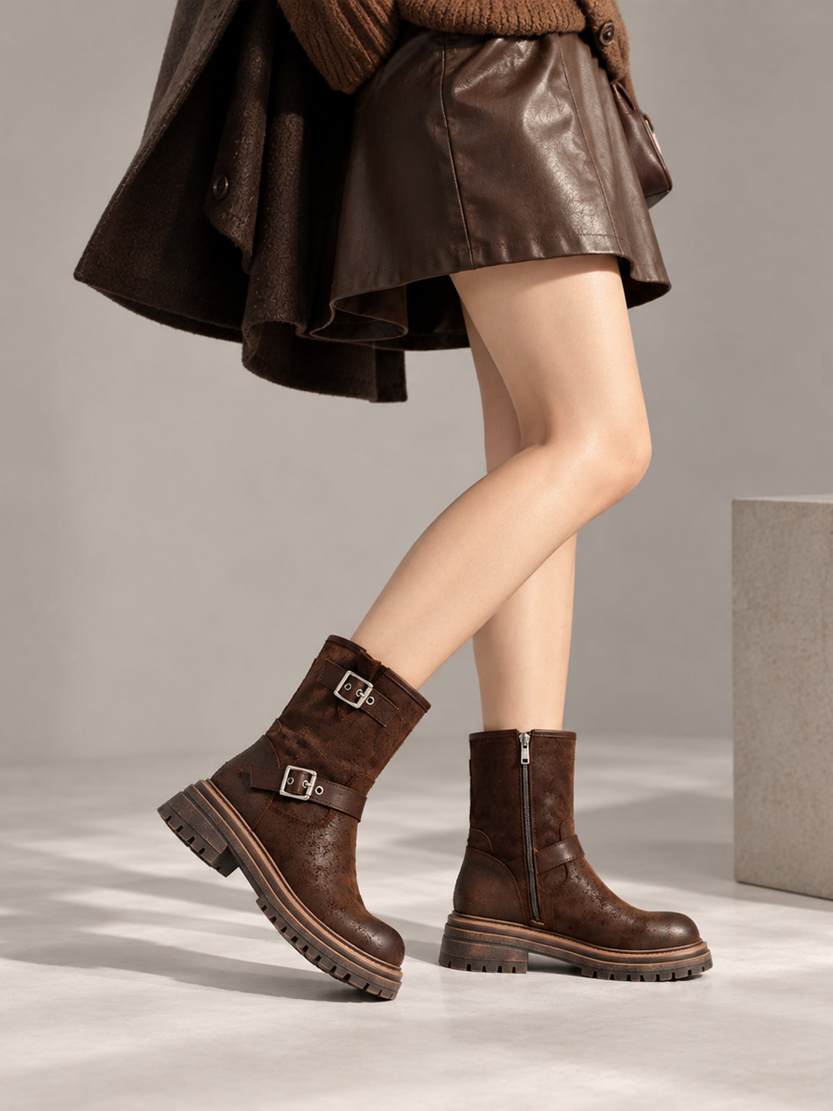 Brown reverse-leather buckle boots, close-up of the shoes being worn.