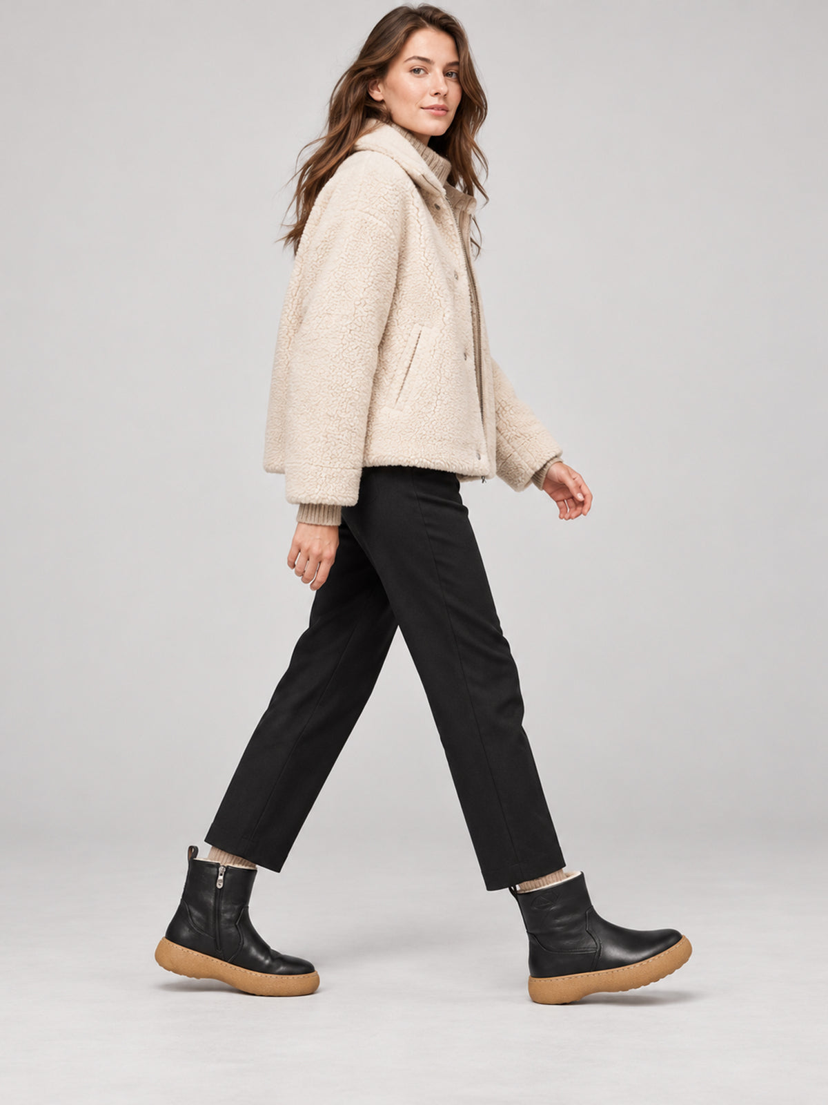 Black polished winter boots with tan soles, shown as part of a complete outfit.