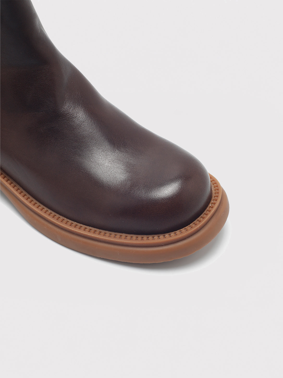 Dark brown washed-leather Chelsea boots, close-up of the toe and sole edge.