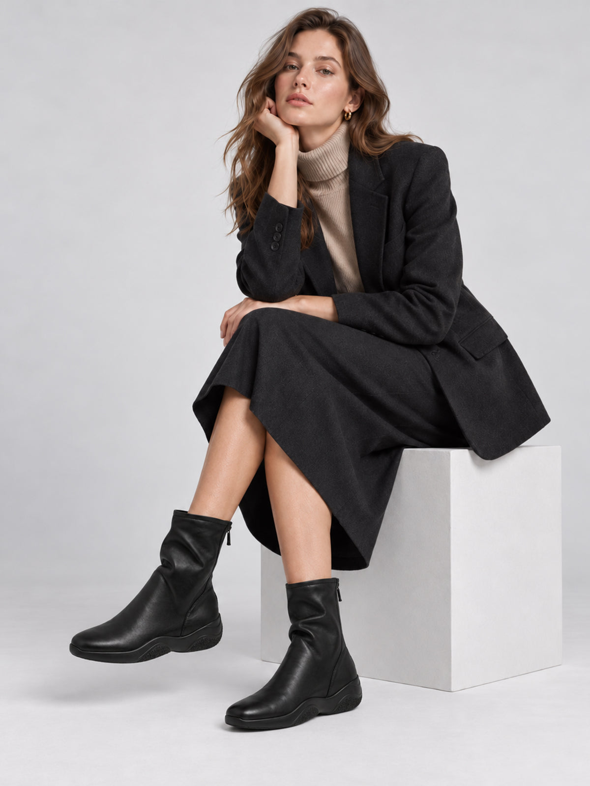 Black lambskin sock boots, worn in a seated outfit.