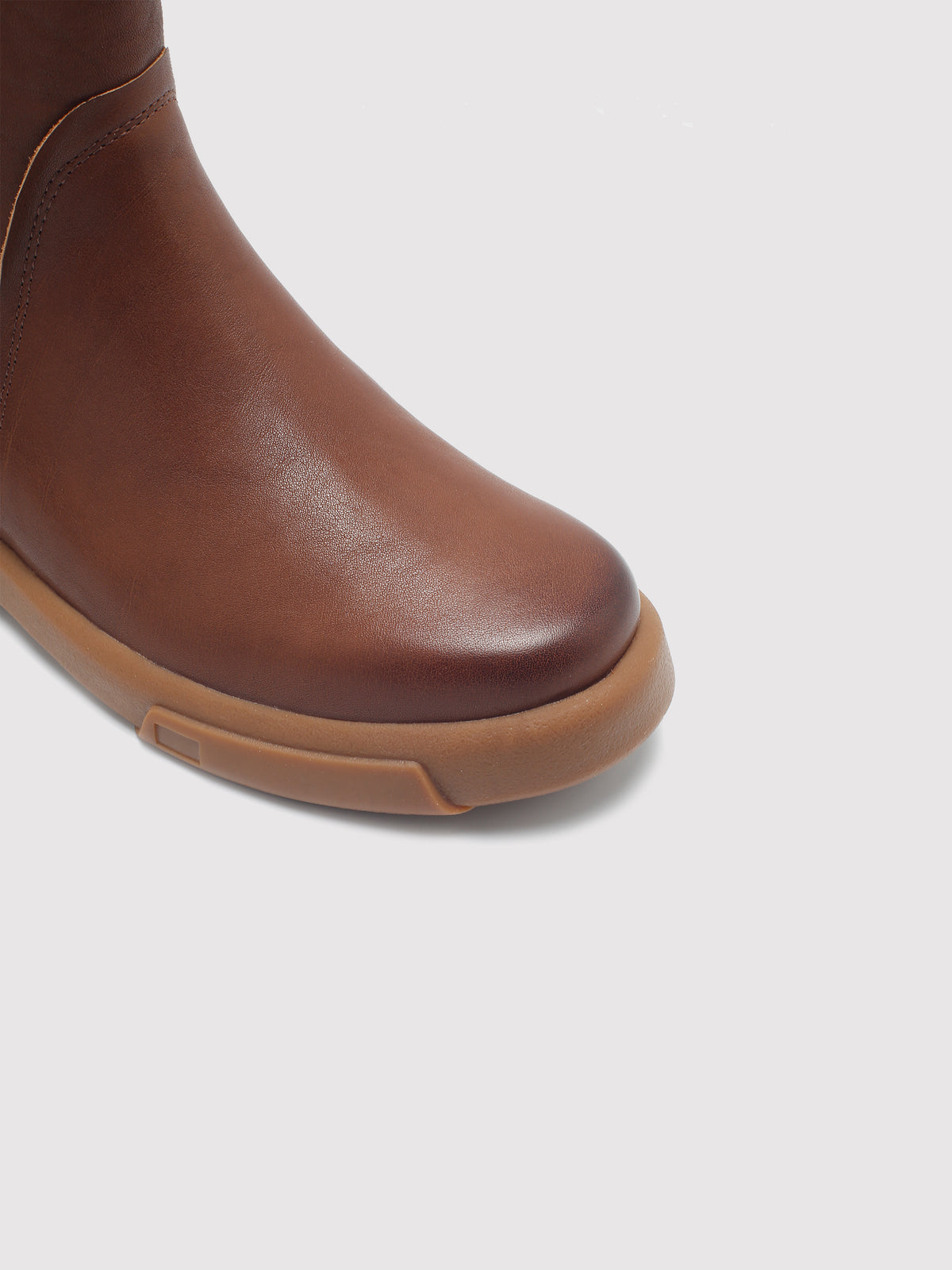 Brown double-zip leather boots, close-up of the toe and sole edge.