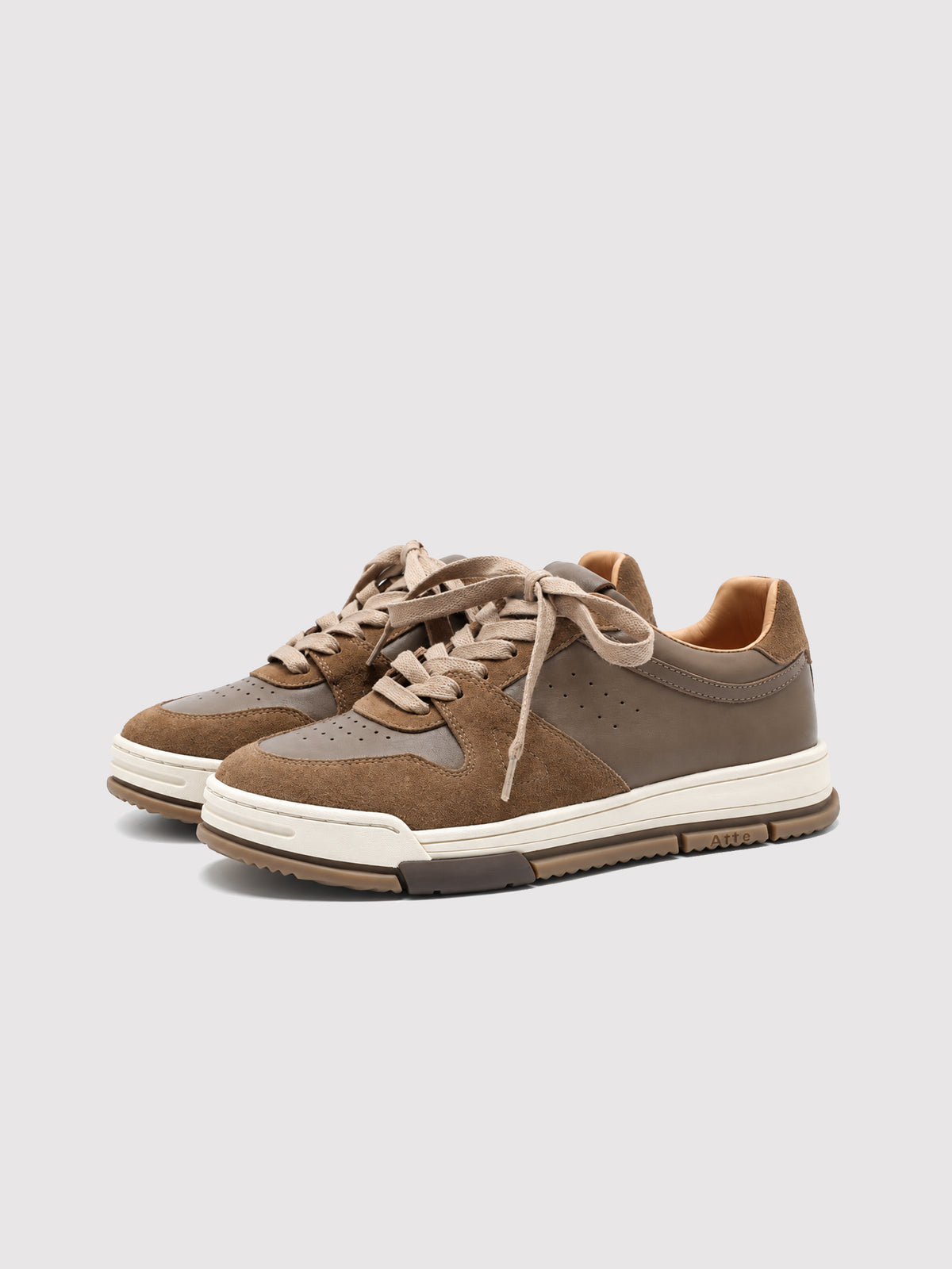 Pair of brown leather and suede sneakers with cream soles.