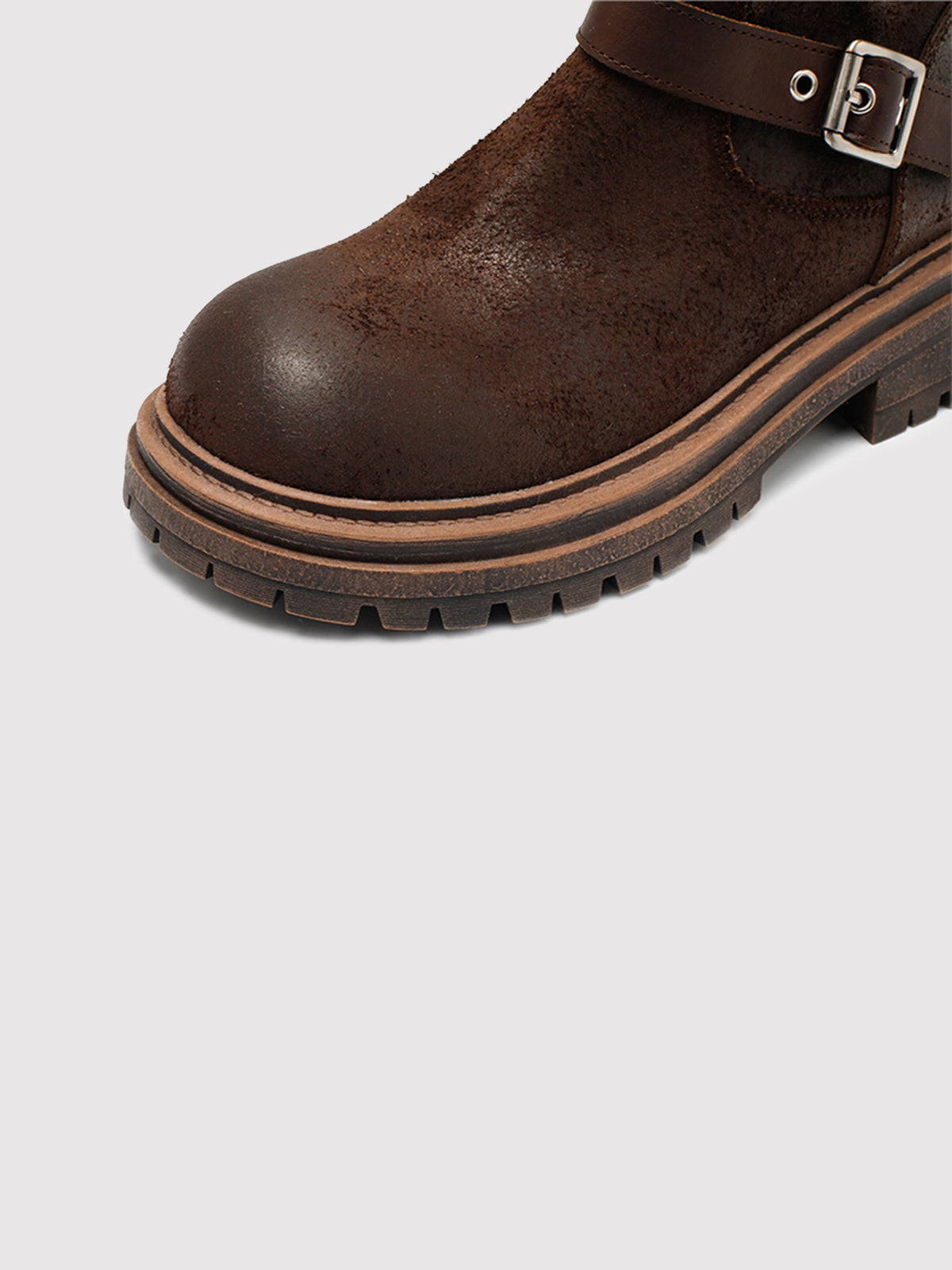 Brown reverse-leather buckle boots, close-up of the toe and sole edge.
