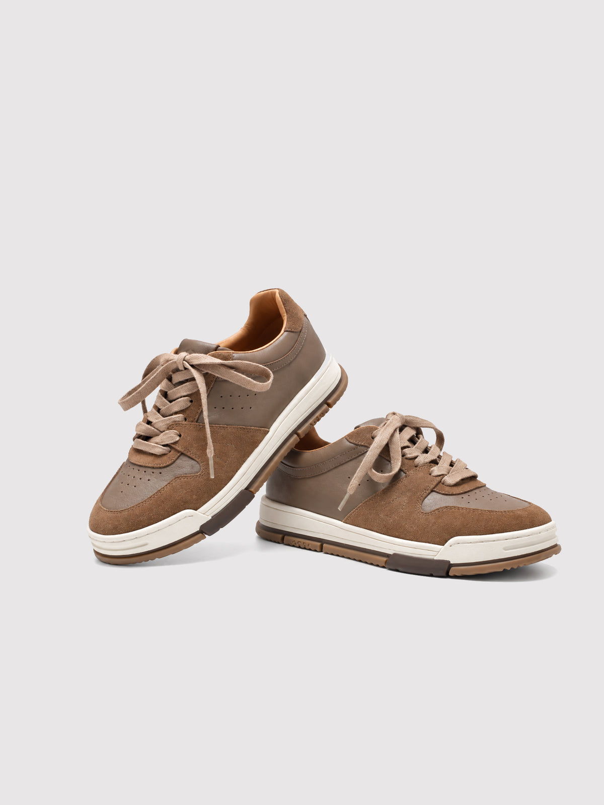 Brown lace-up sneakers with one shoe resting against the other.