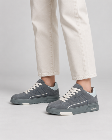 Gray lace-up sneakers, side close-up with cream trousers.