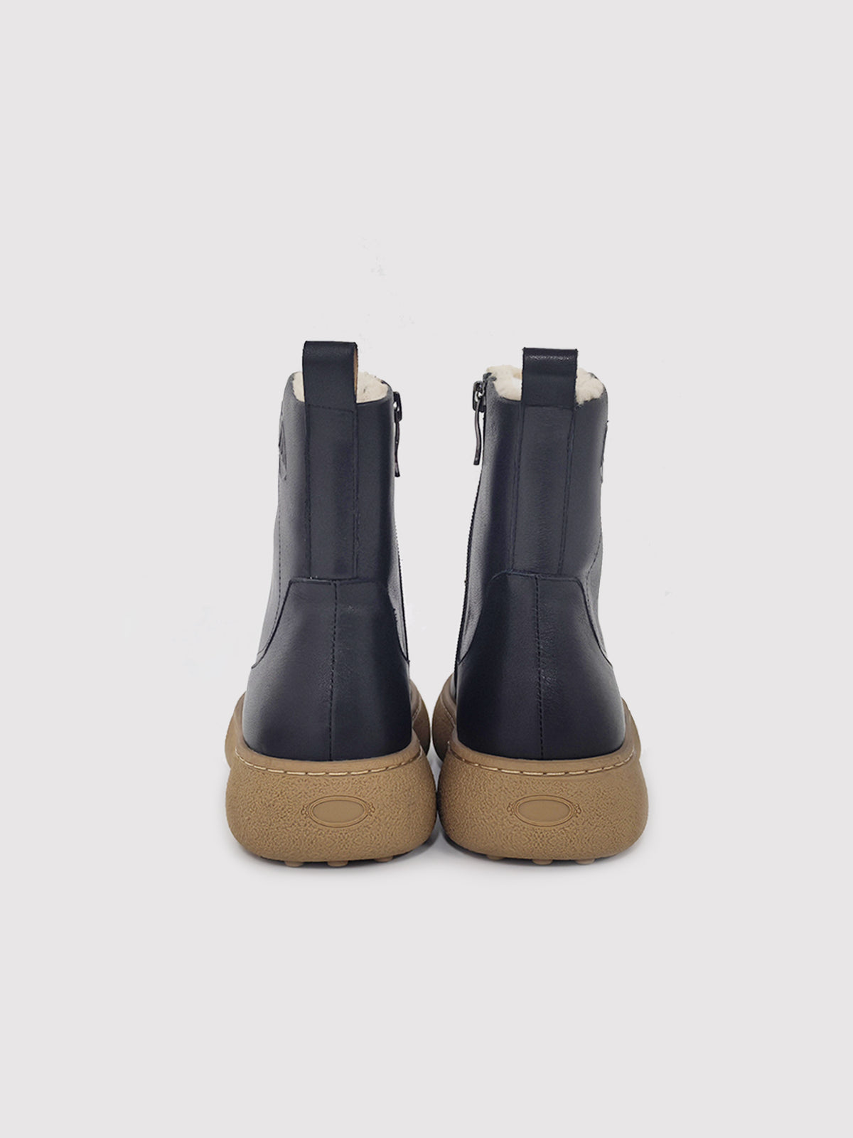 Black polished winter boots with tan soles, pair viewed from the back.