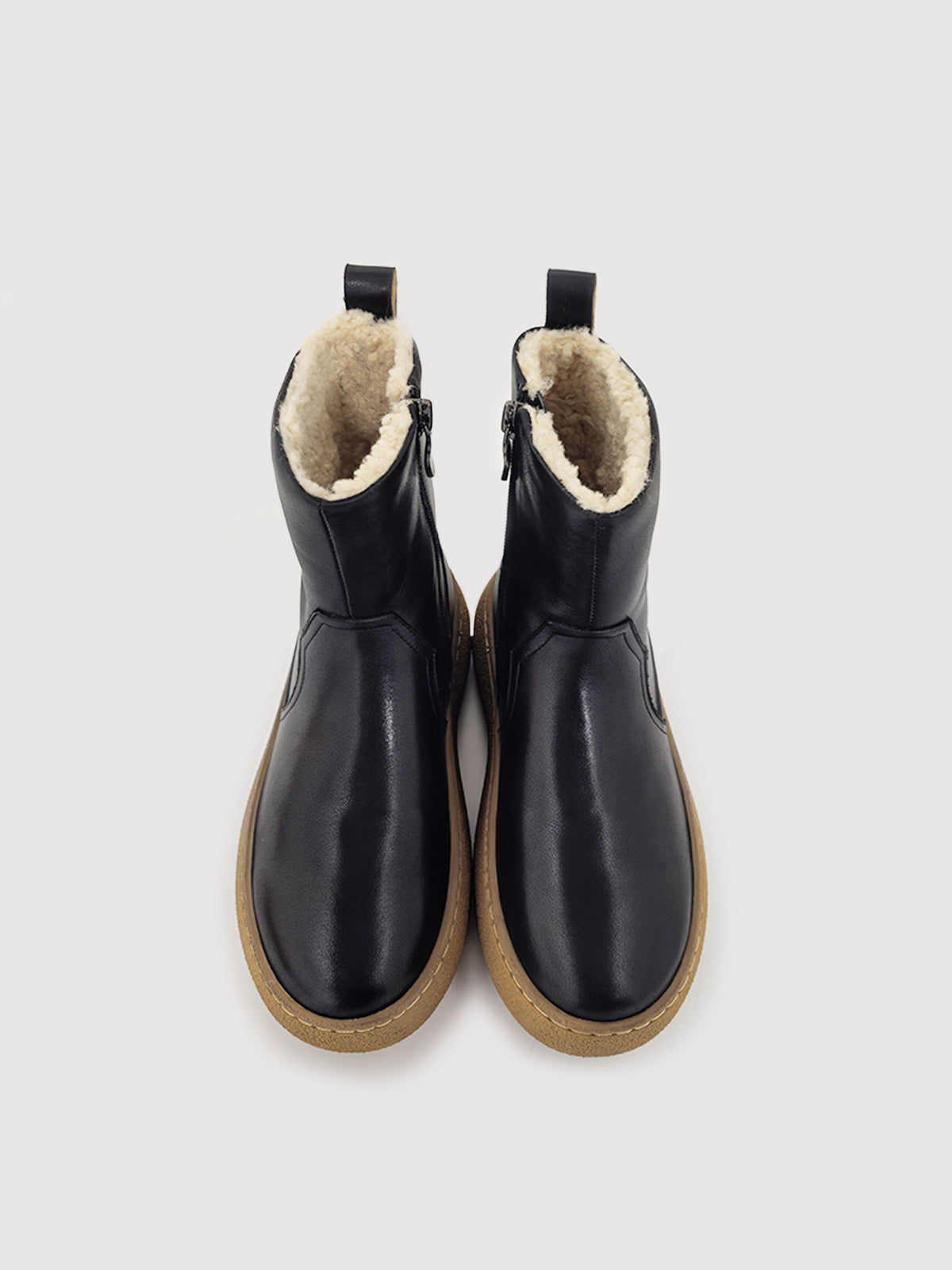 Black polished winter boots with tan soles, pair viewed from above with the lining visible.