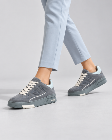 Gray lace-up sneakers, walking close-up with blue trousers.