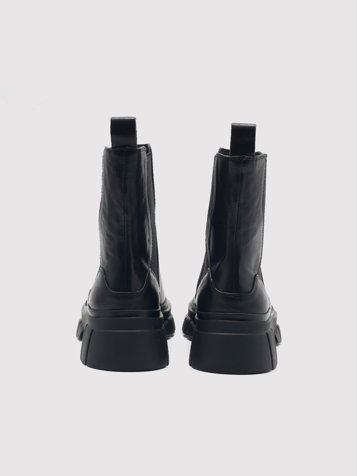Black shaft boots with lug soles, pair viewed from the back.