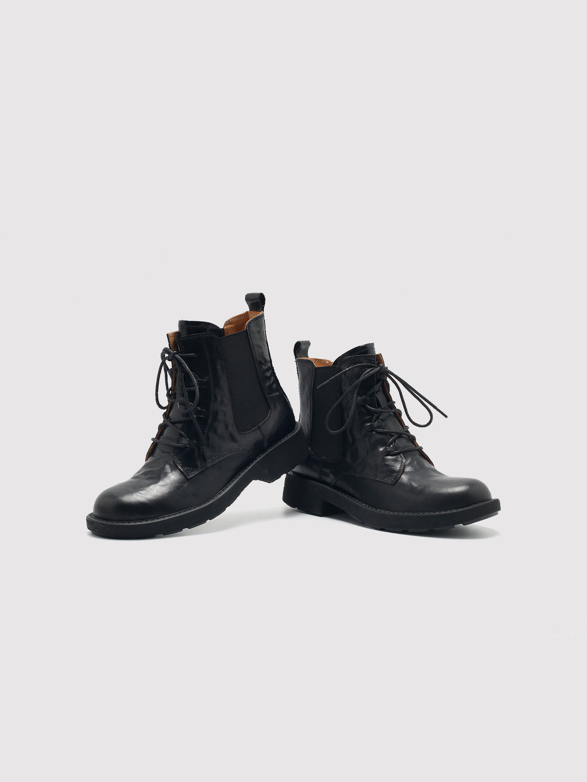Vegetable-tanned black lace-up boots, pair arranged at different angles.