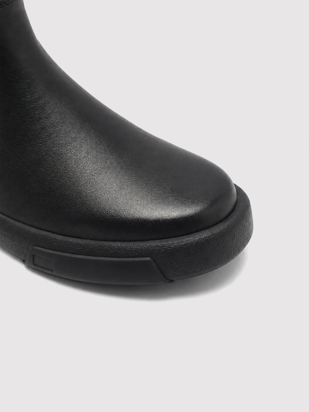 Black zip ankle boots, close-up of the toe and sole edge.