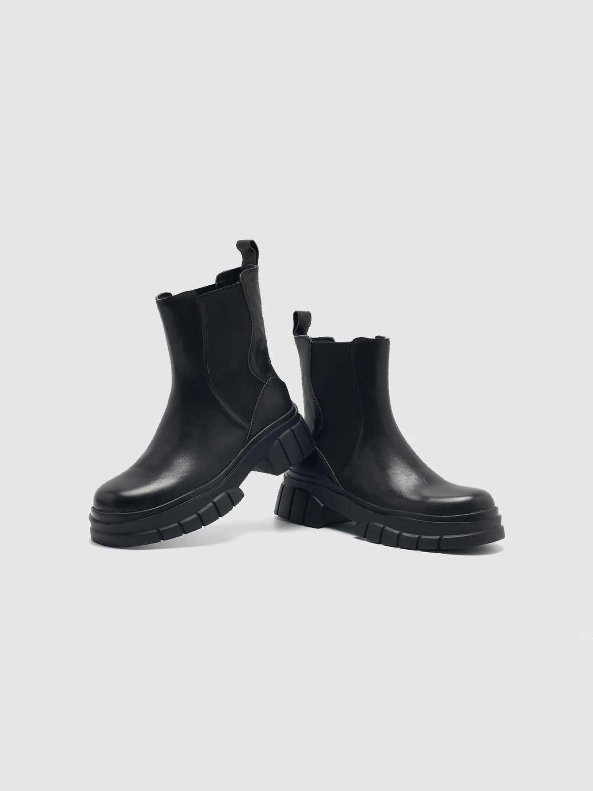 Black shaft boots with lug soles, pair arranged at different angles.
