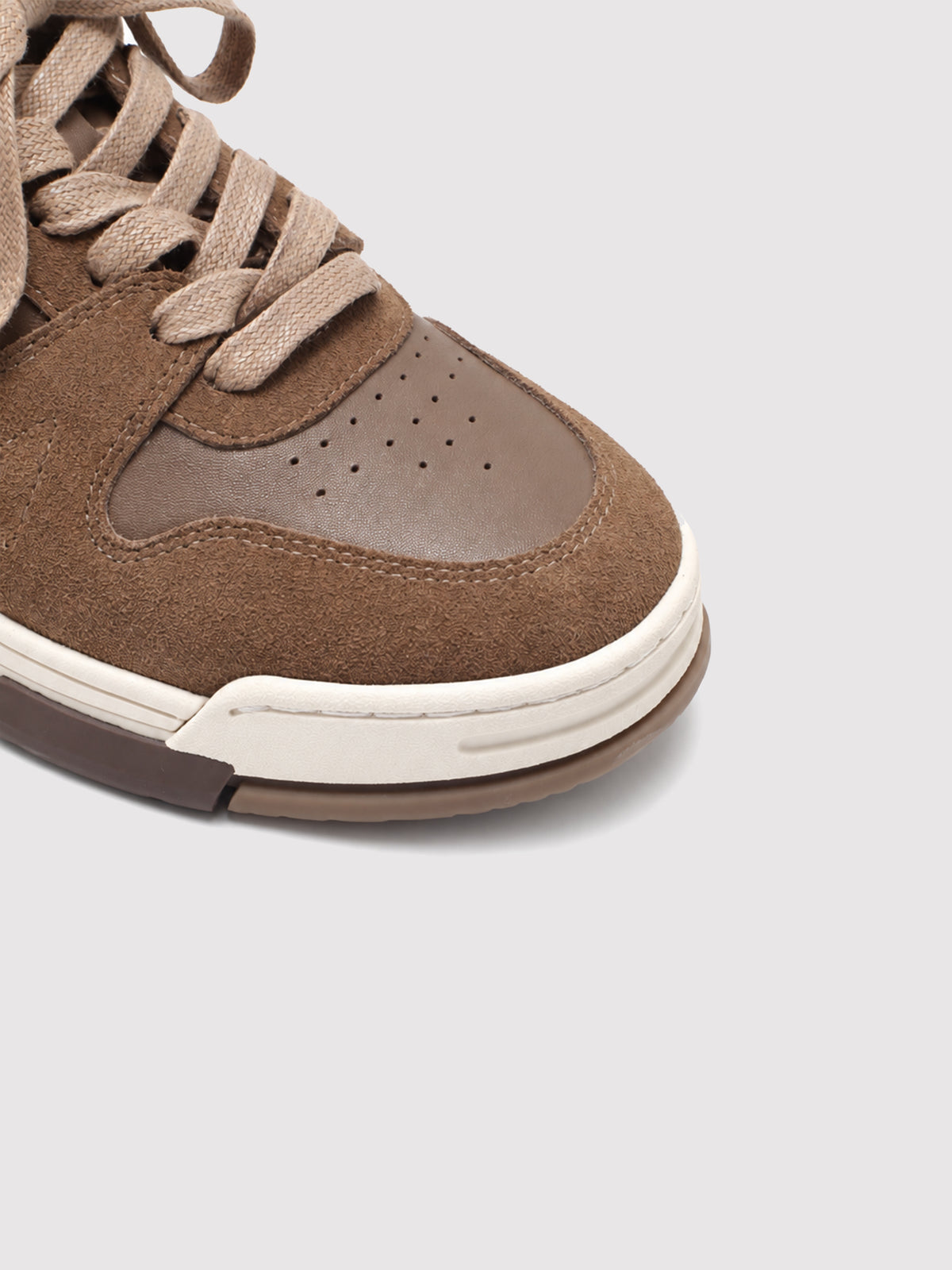 Close-up of the brown sneaker's perforated toe and suede panels.
