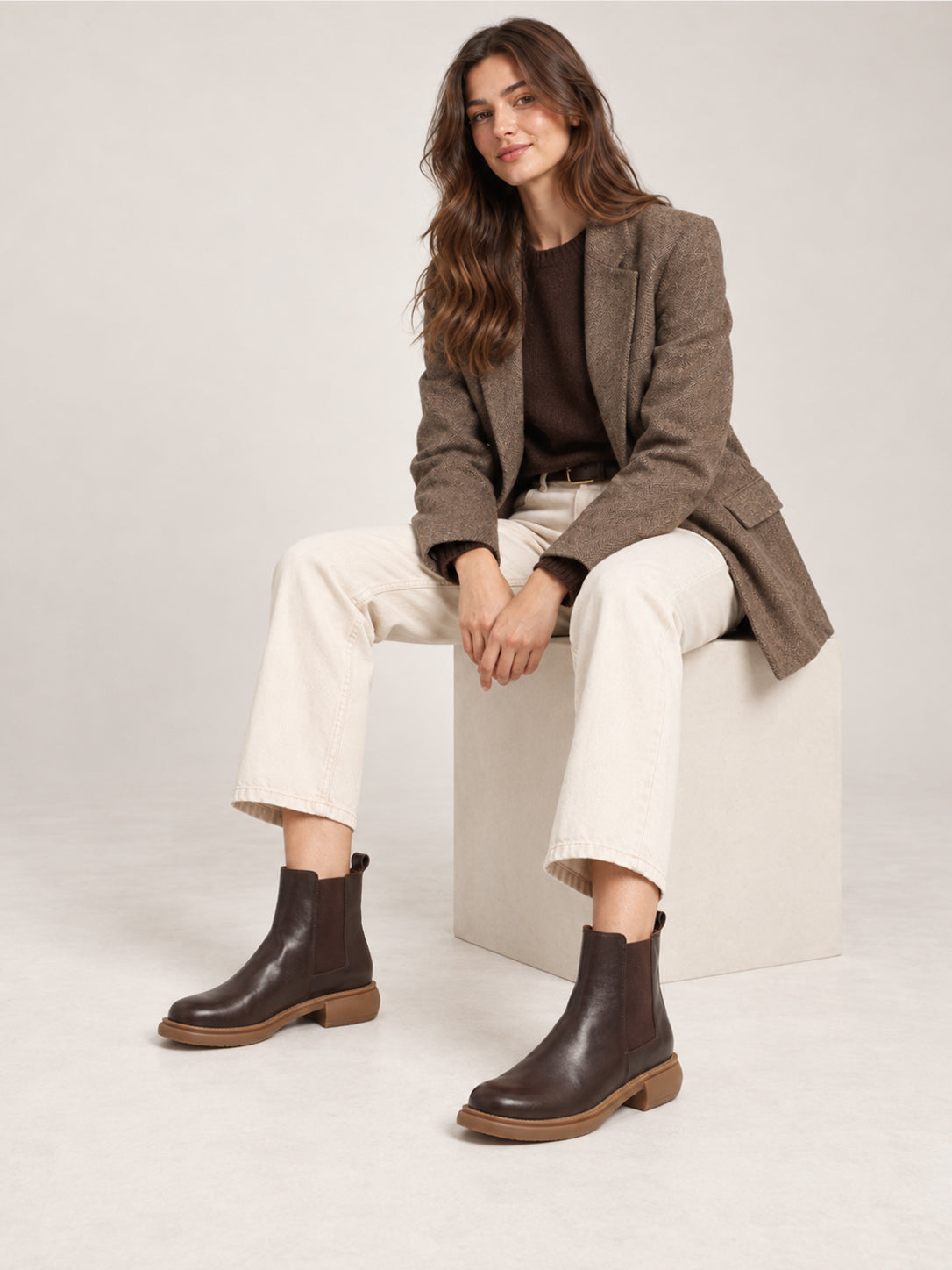 Dark brown washed-leather Chelsea boots, worn with cream trousers in a seated outfit.