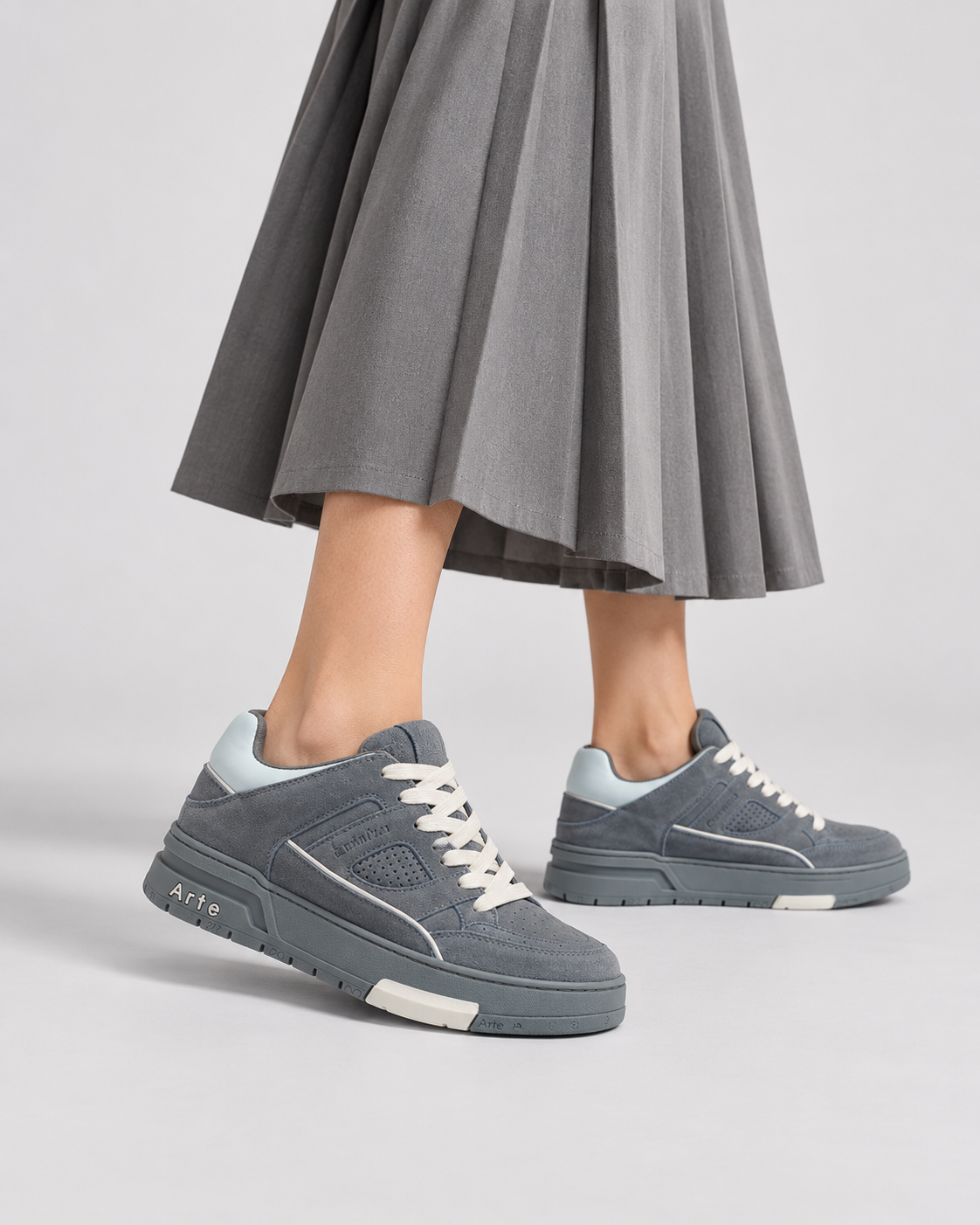 Grey Two-Way low-top sneakers, worn with a grey pleated skirt, close-up.