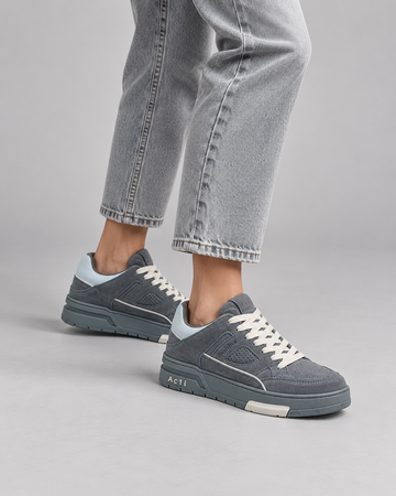 Gray lace-up sneakers, rear close-up with cropped jeans.