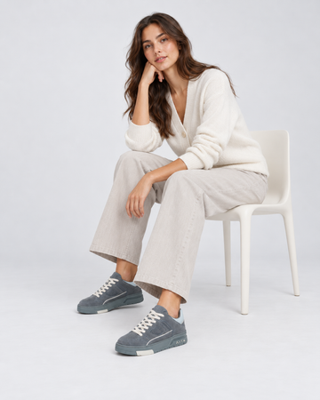 Gray lace-up sneakers, worn with light trousers while seated.