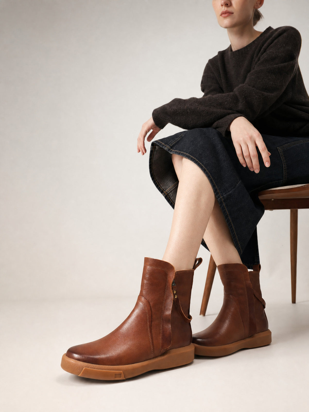 Brown double-zip leather boots, worn with a black outfit while seated.